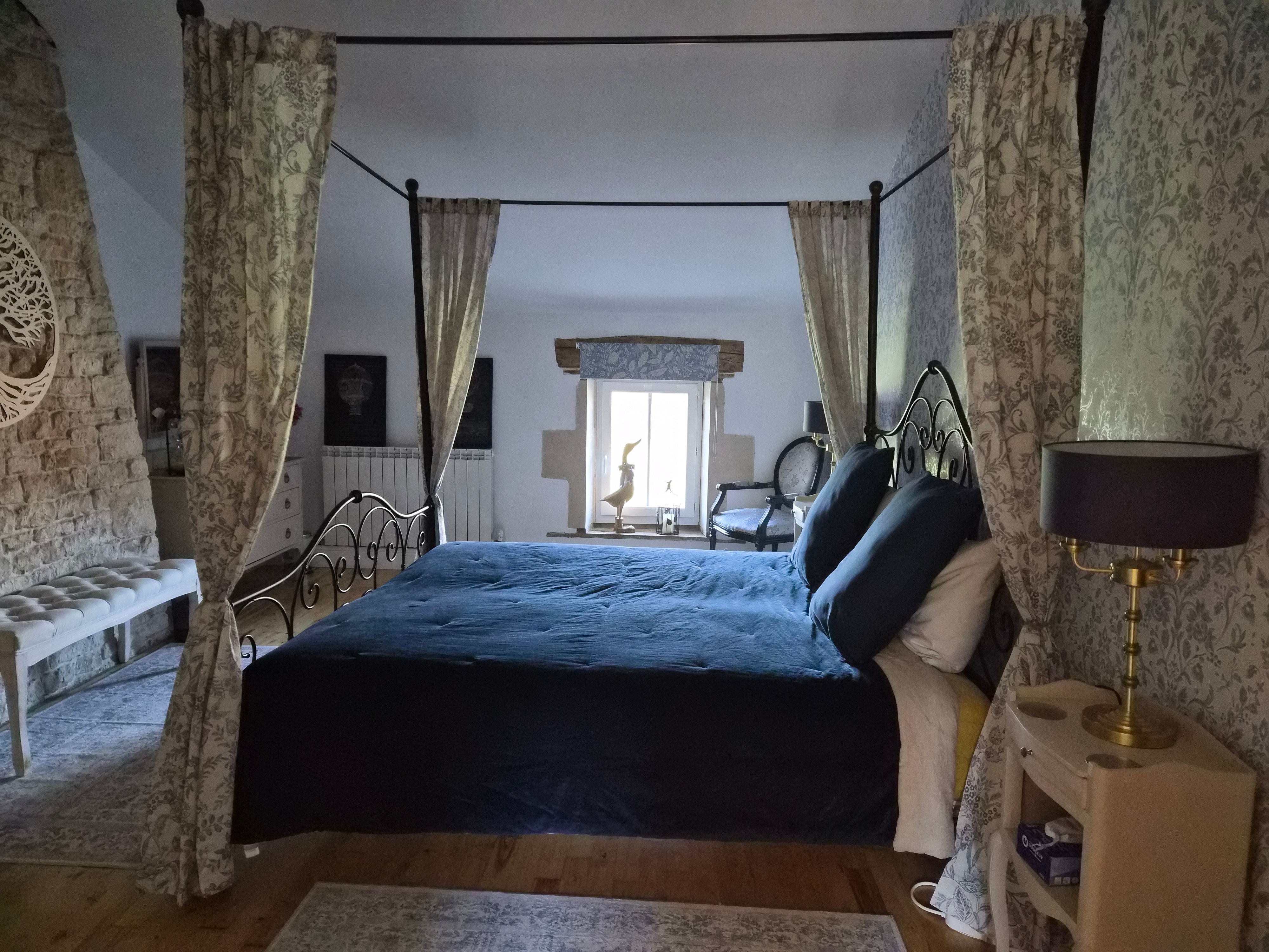 Master bedroom with iron four-poster bed and floral curtains