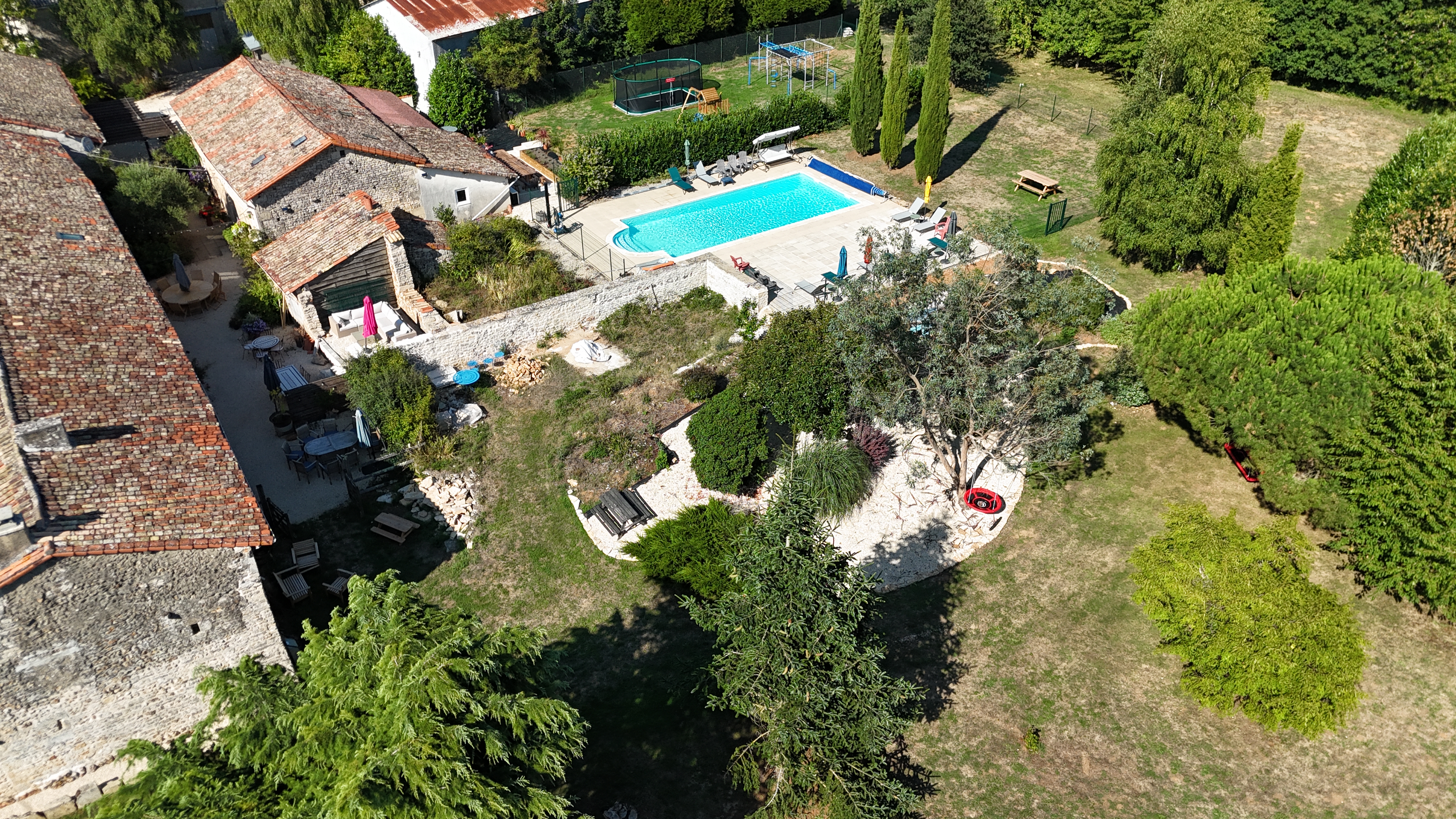 Aerial view of the Gîte du Bois Renard stone farmhouse, pool and surrounding countryside